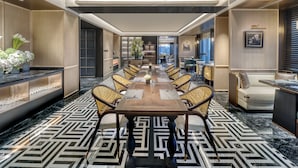 A long dining table with chairs, a sofa, and a TV in a modern hotel room. - Ascott Hankou Riverside Wuhan (Wuhan)
