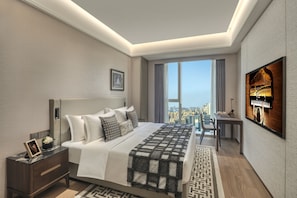 A modern hotel room with a large bed, a desk, a TV, and a city view.