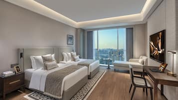Una habitación de hotel moderna con dos camas, un escritorio, una silla, un televisor y vistas a la ciudad.