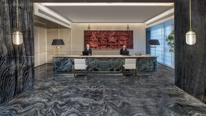 A reception desk with two staff members, a marble floor, and a large wall with intricate patterns. - Ascott Hankou Riverside Wuhan (Wuhan)