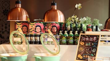 Un rincón cocina con lámparas colgantes de cobre, una exhibición de pepinillos en vinagre y un menú en una pizarra.