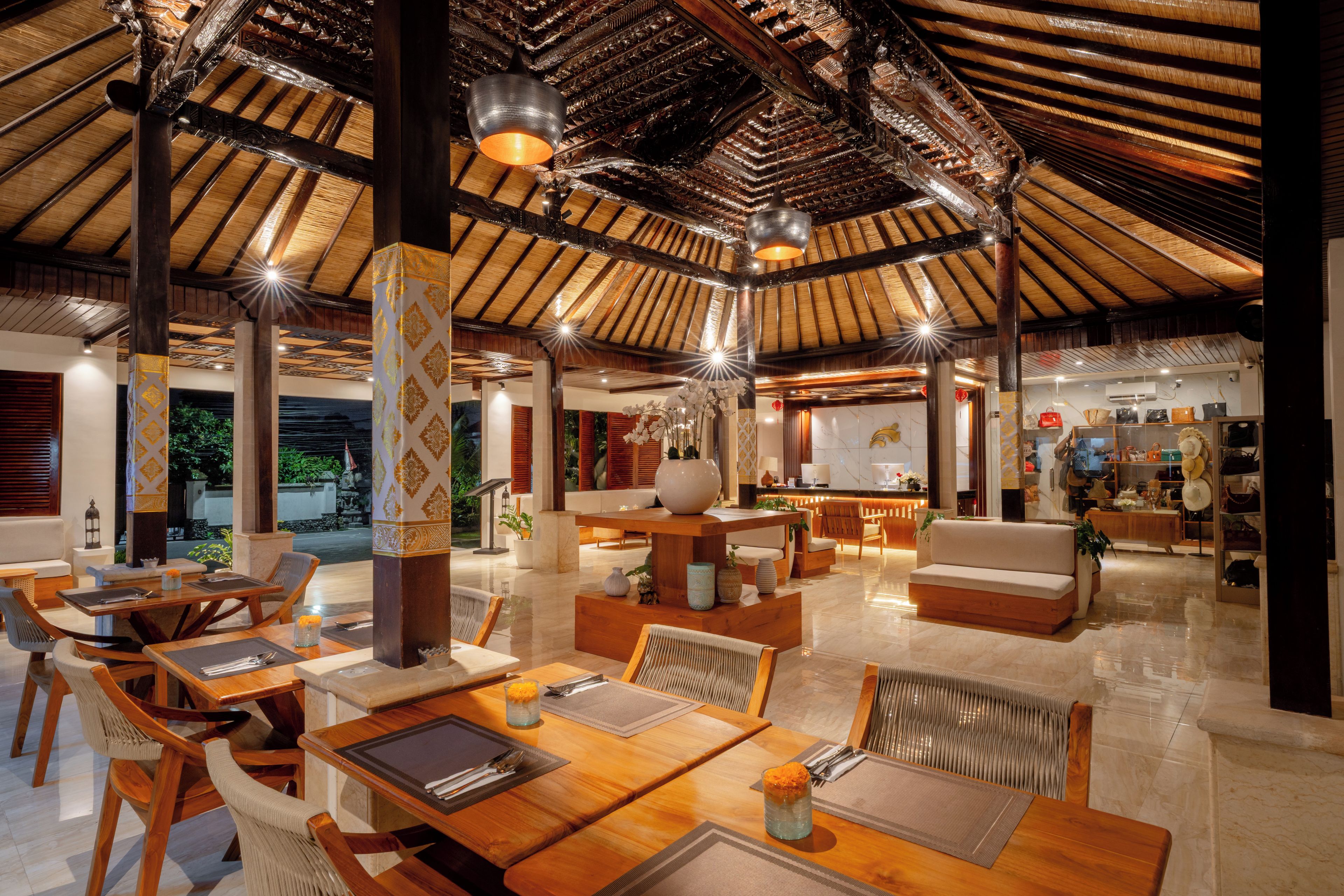A spacious indoor area with a high ceiling, wooden furniture, and a seating area with a view of the outdoors.