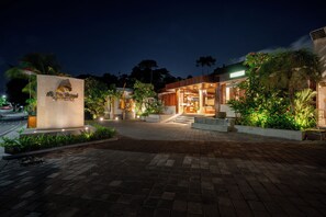 A hotel entrance with a paved driveway leading to a well-lit reception area. - The Prime Seminyak (Kerobokan)