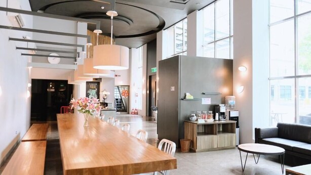 A modern interior with a long wooden table, seating, a kitchenette, and large windows. - Yoai Jiaoxi Spring Hotel (Jiaoxi)