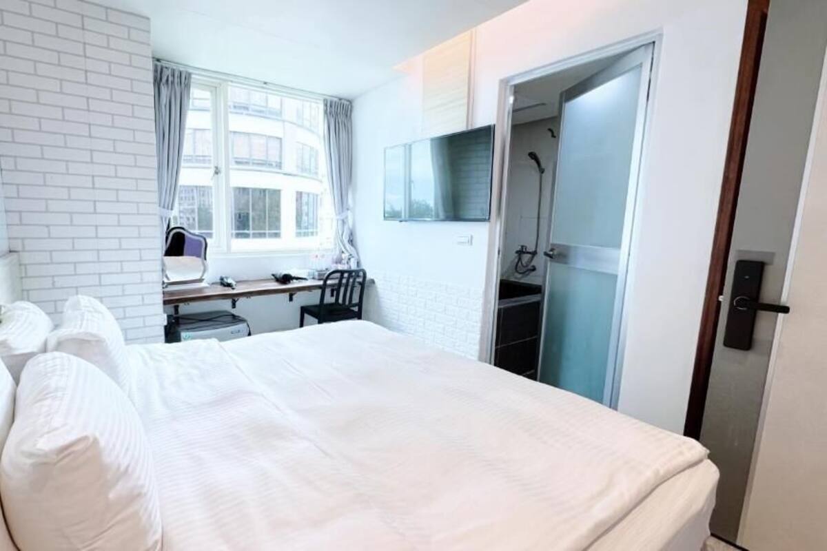 Ein Hotelzimmer mit Bett, Schreibtisch, Stuhl, Fernseher und Duschbereich.