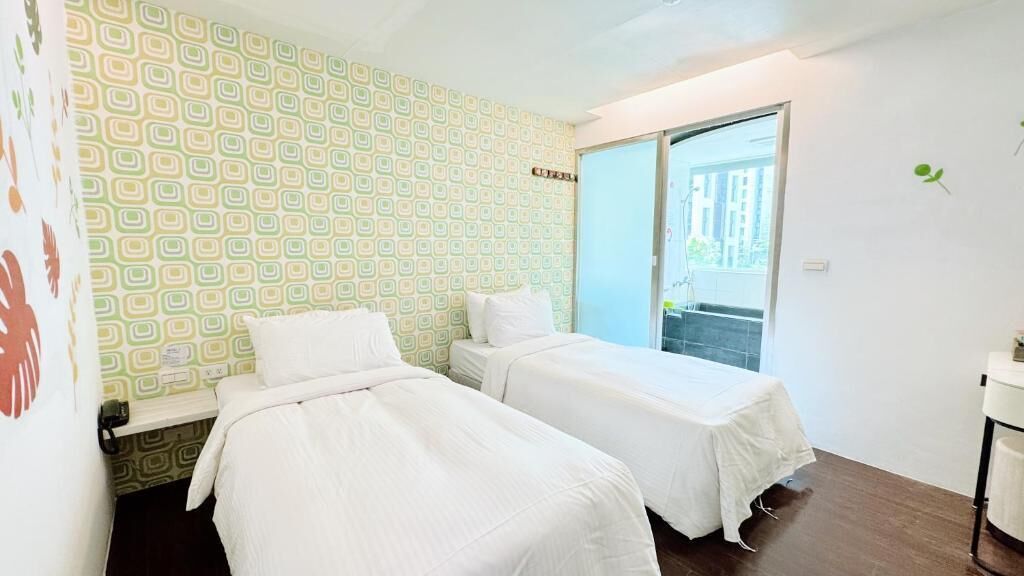 A room with two beds, a window, and a door leading outside.