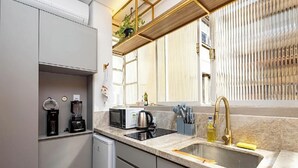Ett modernt kök med inbyggd diskmaskin, mikrovågsugn, kaffebryggare och en diskho med en guldbrun kran.
