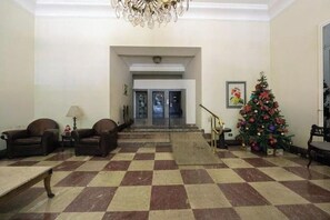 A lobby with checkered flooring, a Christmas tree, and a staircase leading to an entrance. - Lux Casa SP • 3BR + Private Studio • Av. Paulista, Bela Vista, Downtown (São Paulo)