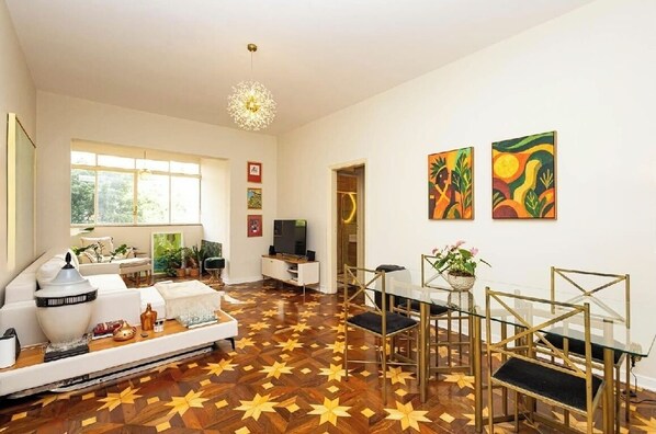 A modern living room with a sofa, TV, dining area, and artwork on the walls. - Lux Casa SP • 3BR + Private Studio • Av. Paulista, Bela Vista, Downtown (São Paulo)
