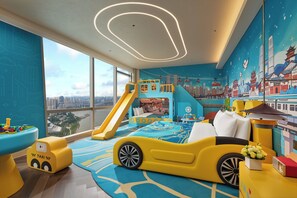 Una sala giochi per bambini con uno scivolo, un letto a forma di automobile e un murale raffigurante un paesaggio urbano.