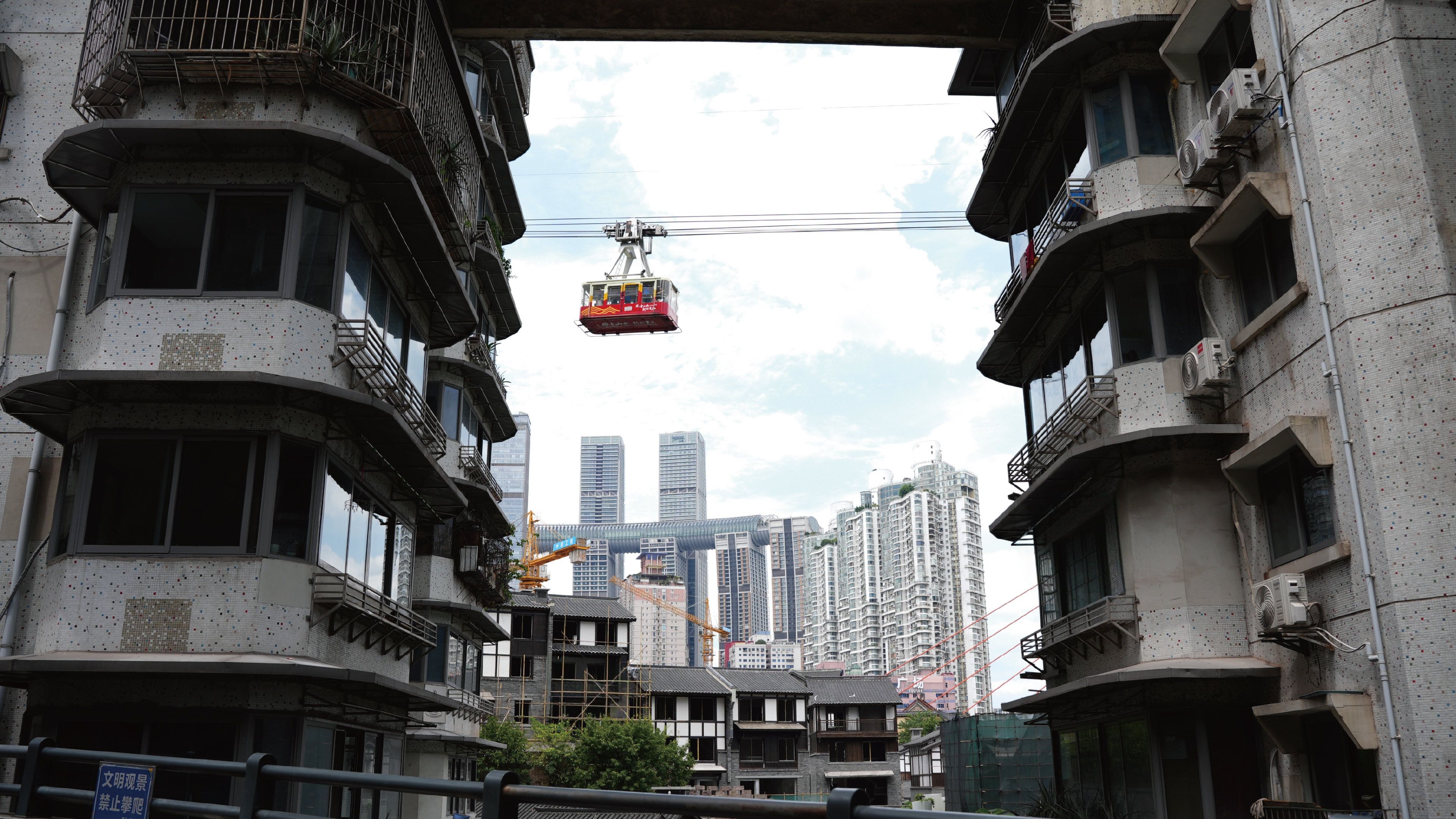 A building with multiple floors, balconies, and a construction crane in the background.