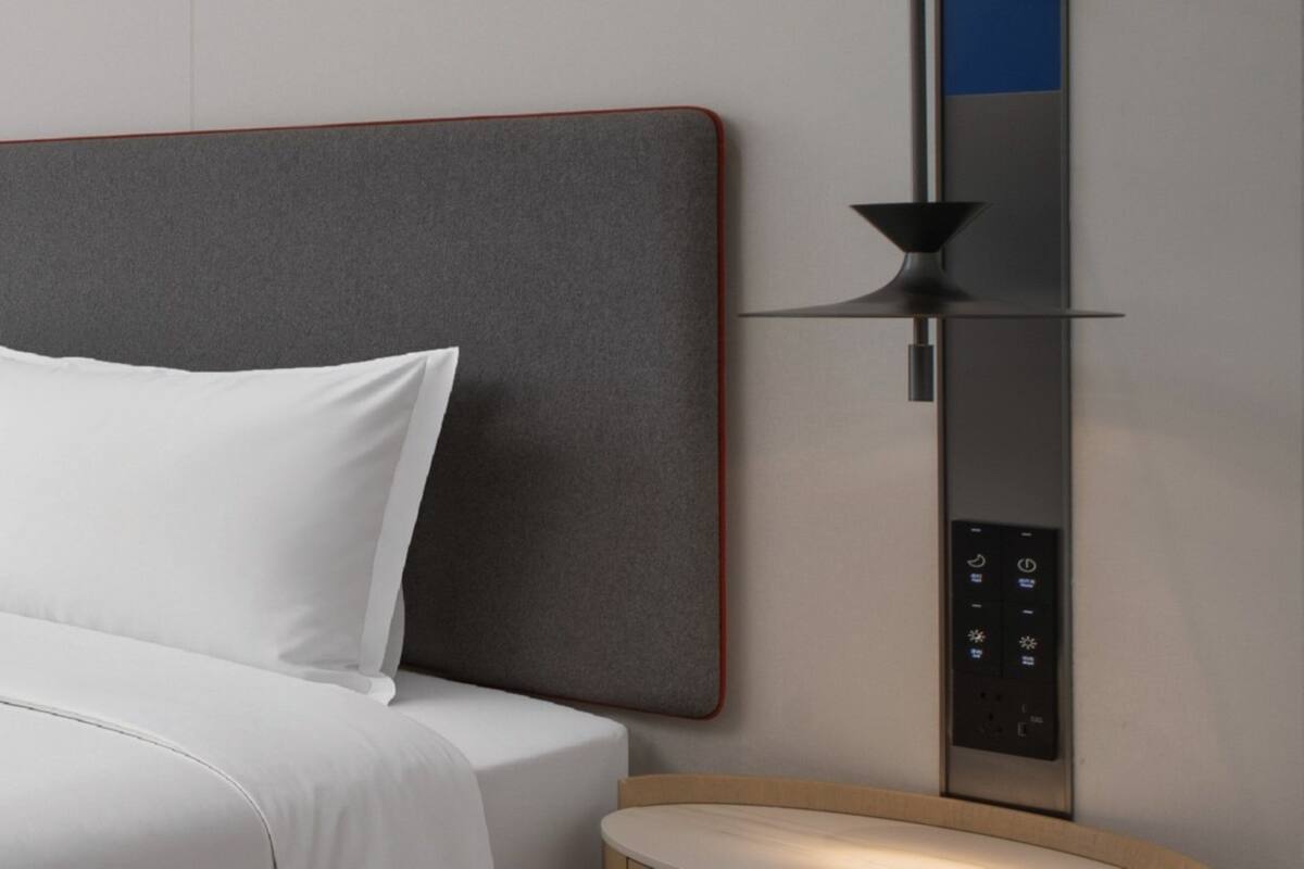 Ett modernt hotellrum med en stor säng, en kontrollpanel och en minimalistisk design.