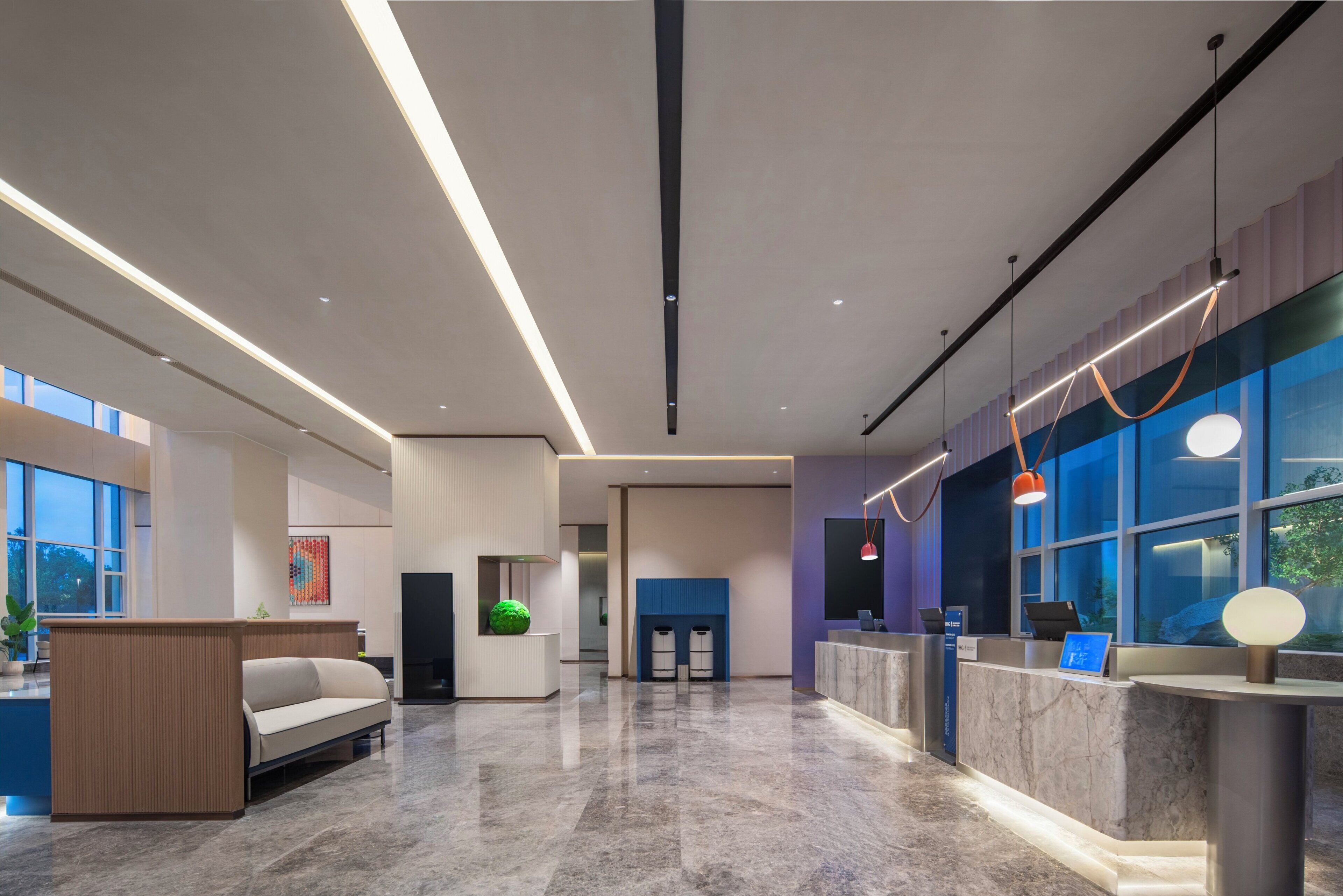 Un lobby moderno con mostrador de recepción, zona de estar y ventanas amplias.