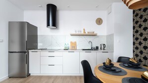 Eine moderne Küche mit einem Edelstahl-Kühlschrank, einer schwarzen Dunstabzugshaube und einem Holzespeisesatz mit schwarzen Tellern und Schüsseln.
