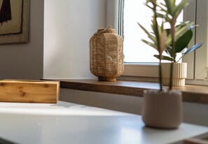 Una cesta de mimbre sobre un alféizar, una planta en maceta y un caja de madera.