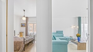 A modern living room with a sofa, a coffee table, and a bed with a headboard. - Holiday On The Sea - Seafront Apt, Menton, France (Menton)