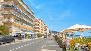 A coastal hotel with multiple balconies, outdoor seating, and a view of the beach. - Holiday On The Sea - Seafront Apt, Menton, France (Menton)