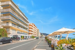 A coastal hotel with multiple balconies, outdoor seating, and a view of the beach. - Holiday On The Sea - Seafront Apt, Menton, France (Menton)