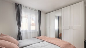 Ein Schlafzimmer mit zwei Betten, einem Kleiderschrank und einem Fenster mit Vorhängen.