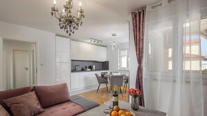 Ein modernes Wohnzimmer mit Sofa, Essbereich und einer Küche im Hintergrund.