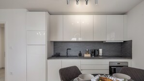 Eine moderne Küche mit weißen Schränken, einer dunklen Arbeitsplatte und einem Essbereich mit Tisch für zwei Personen.