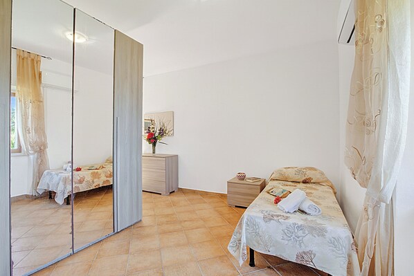 A bedroom with a bed, a bedside table, a mirror, a dresser, and a small nightstand. - Residence Argentiera Room 20 Sea View, Miniera dell’Argentiera, Italy (Miniera dell’Argentiera)