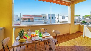 Un balcon avec une table dressée pour le dîner, une chaise et une vue sur les bâtiments.