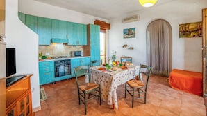 Une cuisine avec des armoires de couleur turquoise, une table à manger avec des chaises et un luminaire suspendu.