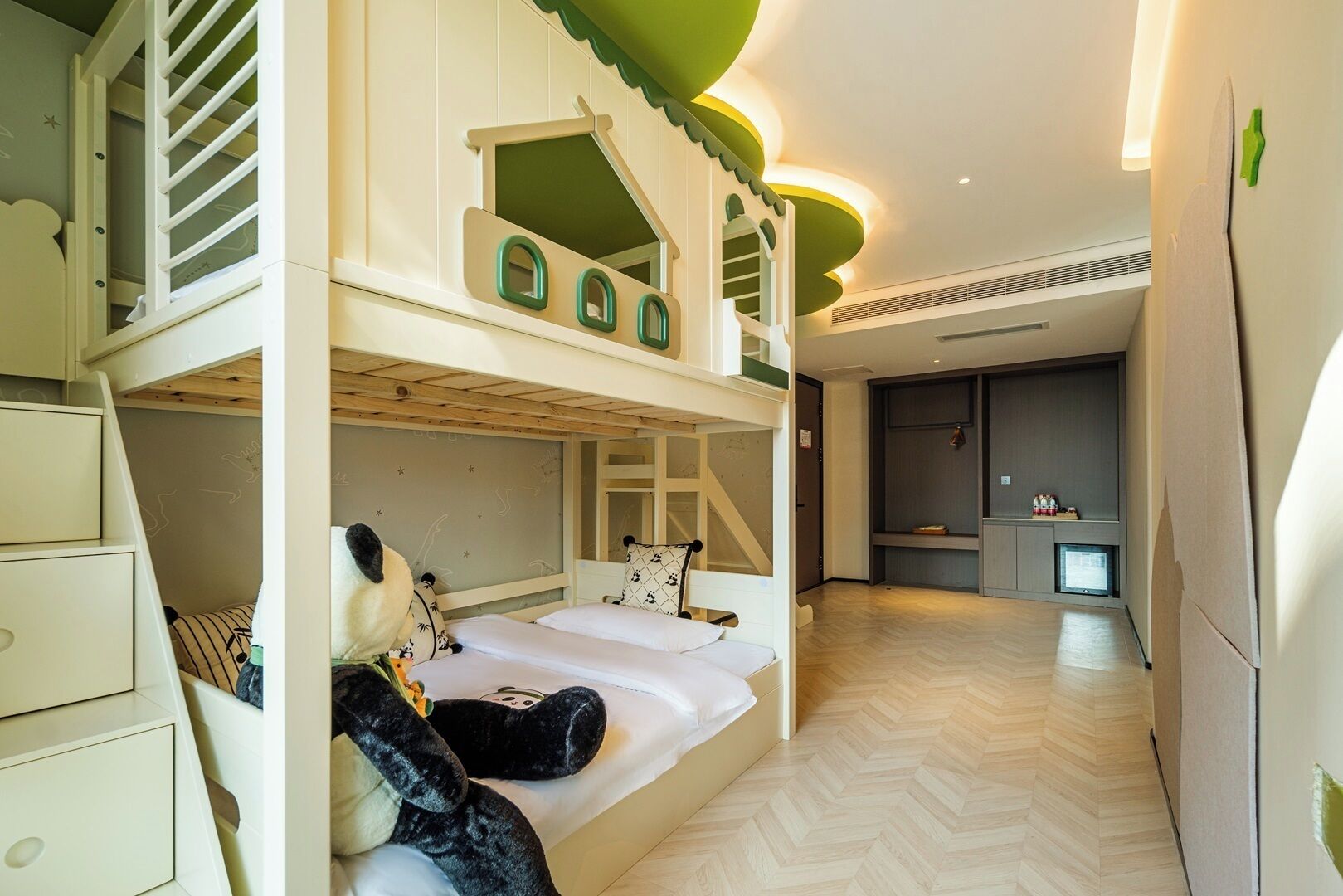 A children's bunk bed with a playhouse design, a small kitchen area, and a herringbone-patterned floor.