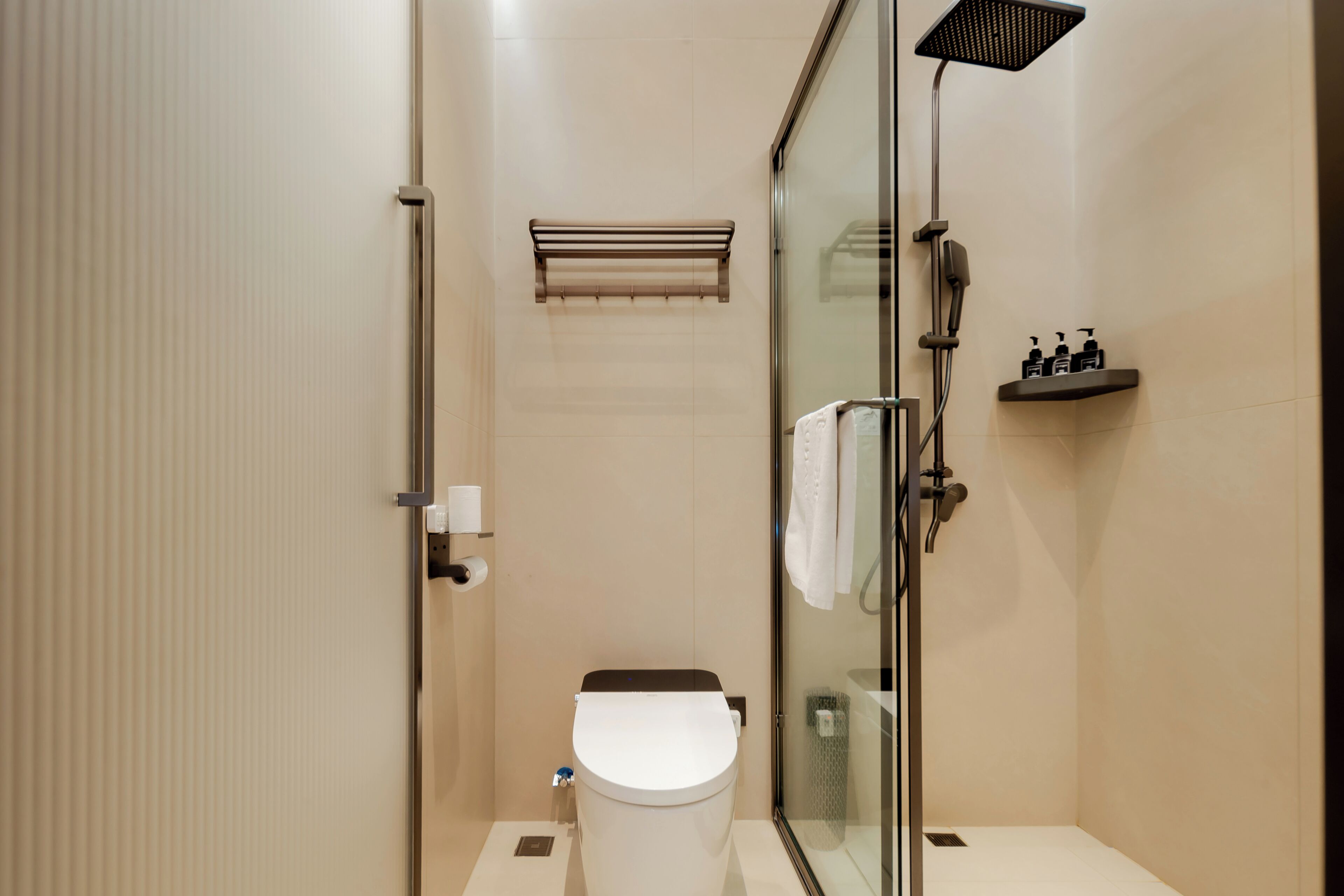 Een moderne badkamer met een douchecabine, toilet en een plank met toiletartikelen.