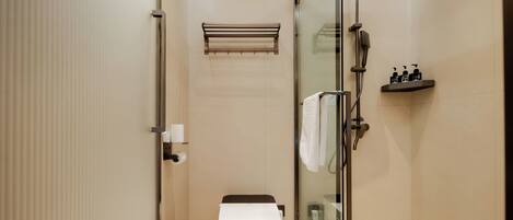 Een moderne badkamer met een douchecabine, toilet en een plank met toiletartikelen.