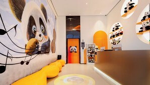 Un interno moderno con un murale a tema panda, una reception e scaffali con peluche a forma di panda.