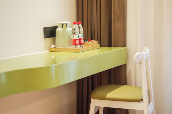 A hotel room with a green countertop, a white chair, and a tray with bottles and a box.