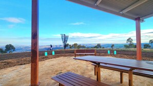 An outdoor seating area with benches and a table, overlooking a scenic landscape.