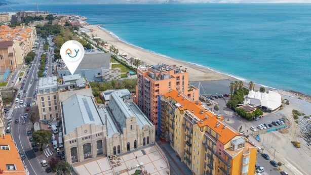 Uma área costeira urbana com edifícios, uma praia e céu claro.