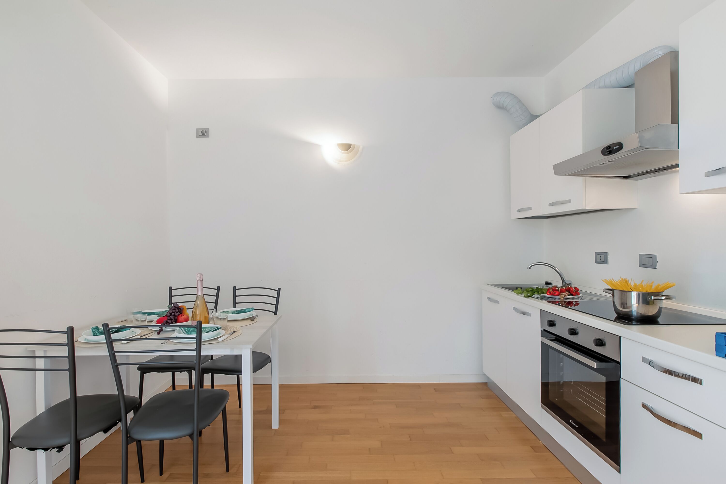 Una cocina compacta con armarios blancos, estufa y pileta.