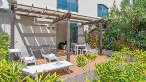 Eine Terrassengruppe mit Pergola, Sitzgelegenheiten und Topfpflanzen.
