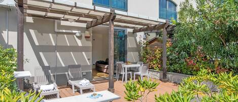 An outdoor patio with a pergola, seating area, and potted plants.