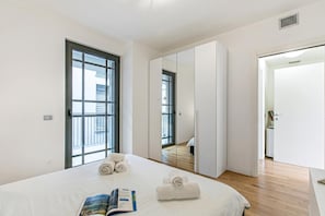 Una habitación de hotel moderna con una cama grande, una ventana, un armario y una puerta que da a un baño.
