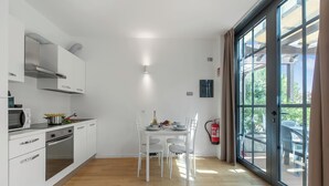 A modern kitchen with white cabinets, a built-in oven, and a dining area with a table and chairs. - Mediterranea 35 in Savona, Savona, Italy (Savona)