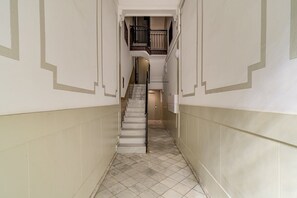 Ein schmaler Flur mit einer Treppe, die zu einer Zwischenebene führt.