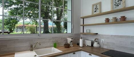 A modern kitchen with a large window, white cabinets, and a wooden countertop.
