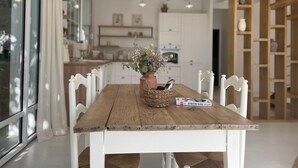 En matplats med ett träbord, vita stolar, en vas med blommor och en korg.