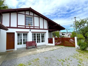 A two-story house with a red door, a bench outside, and a red fence. - HARTZURIENEA - ANHAUX (ANHAUX)