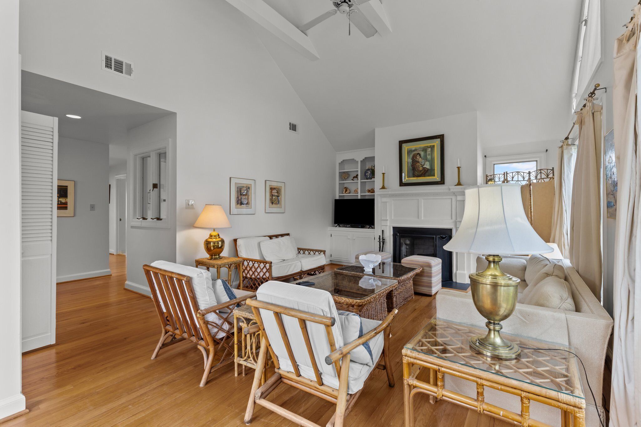 A spacious living room with a fireplace, wicker furniture, and a television.