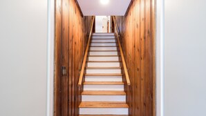 Eine Holztreppe mit weißen Stufen, die zu einer Zwischenebene führt.