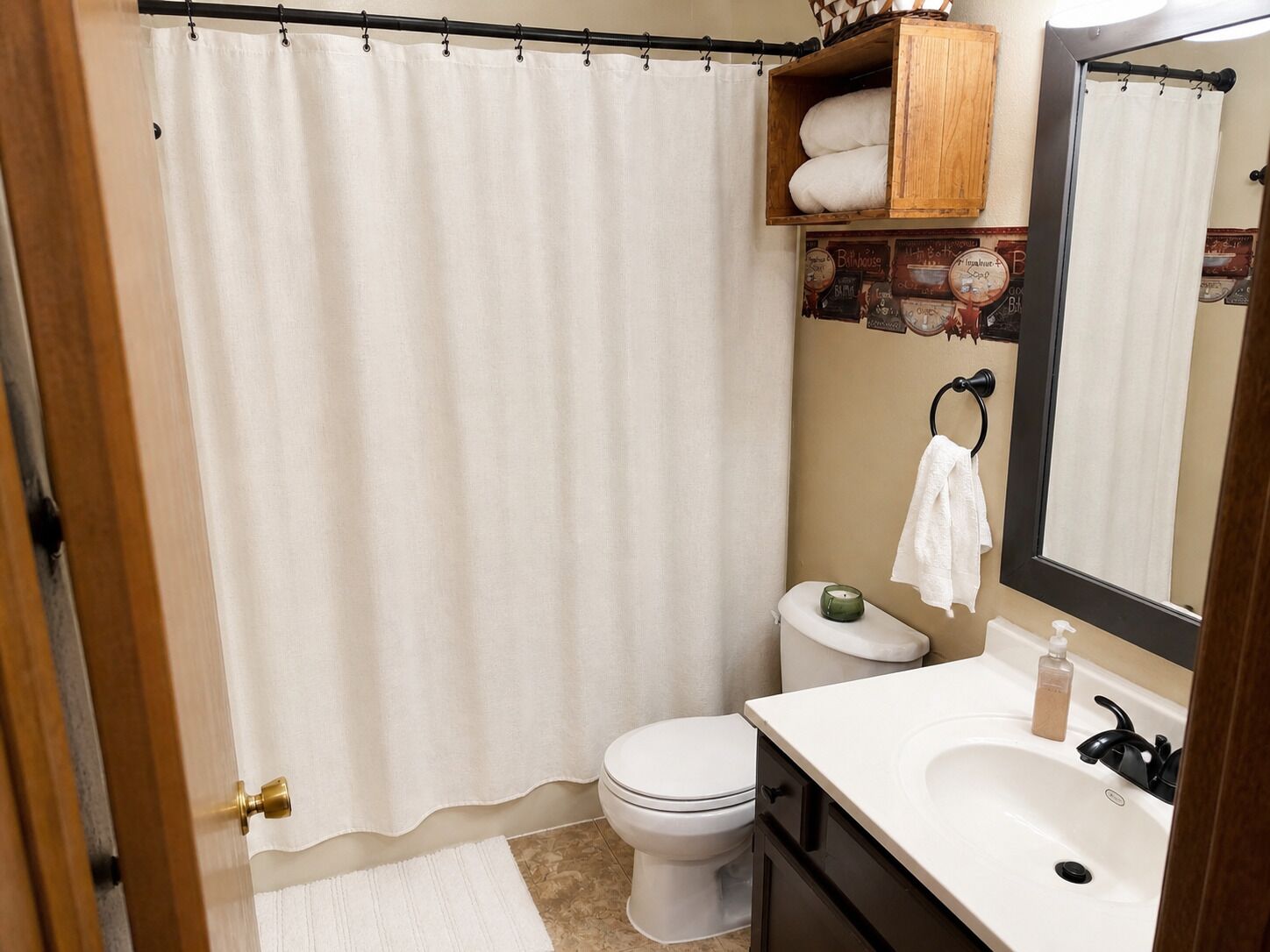 A bathroom with a shower curtain, toilet, sink, and a towel rack.