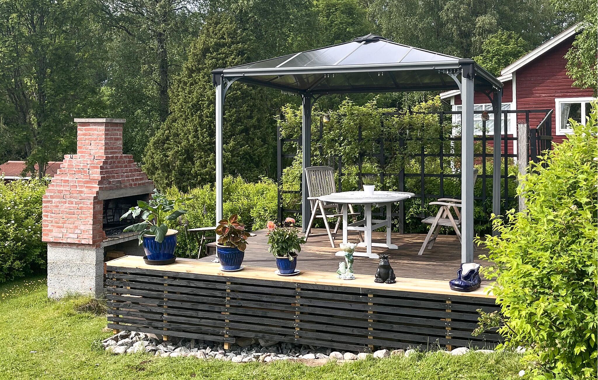 A covered outdoor patio with a brick fireplace, a table and chairs, and potted plants.