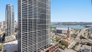 A high-rise building with a grid-like facade, a prominent tower, and a view of a marina with boats and a bridge. - 501 First Luxury Ocean View from Balcony Rooftop Pool & GYM 3510 (Miami)