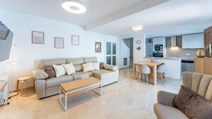 A modern living room with a sofa, coffee table, and dining area. - SR Las Cancelas 3BDR townhouse in Marbella Centre (Marbella)